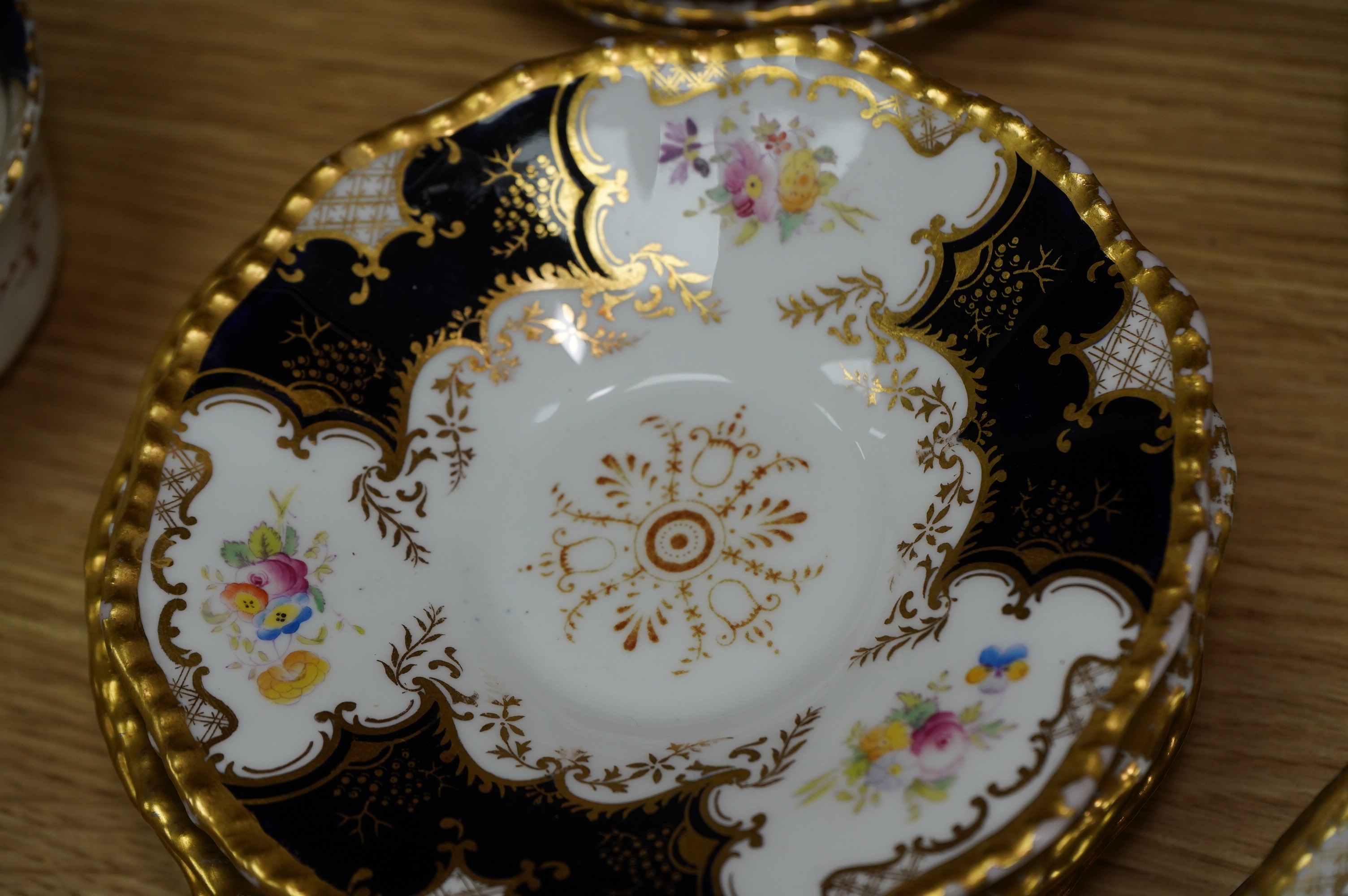 A late 19th/early 20th century Coalport blue and gilt bordered floral painted part tea and dessert service, largest 32cm wide. Condition - varies